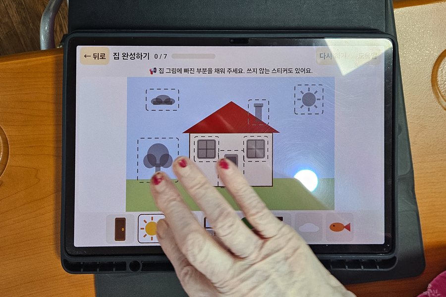 태블릿에서 집 그림을 완성하는 손
